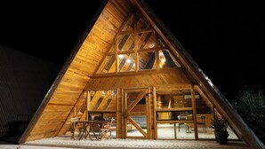 Una estructura de madera triangular con ventanas amplias y una zona de estar.