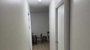 En gang med trægulv, hvide vægge og en lampe i loftet.