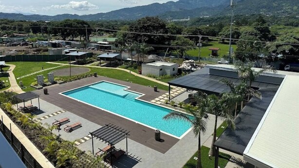 En pool med udsigt til bjerge, en overdækket terrasse og en parkeringsplads.