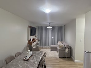 A modern living room with a dining area, a sofa, a TV mounted on the wall, and a ceiling light. - Spacious 3-bedroom apartment with AC in superb San Rafael (San Rafael)