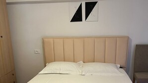 Sängyssä on pääty, valkoiset vuodevaatteet ja pyyhe on asetettu sängylle.