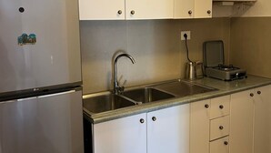 Keittiössä on valkoiset kaapit, ruostumattomasta teräksestä valmistettu pesuallas, LG:n jääkaappi ja kahvinkeitin.