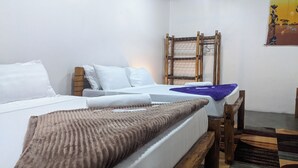 A room with two beds, a wooden chair, a hanging rack, and a wall painting. - Kay's Place Cultural Apartment Zanzibar Gallery (Zanzibar)