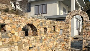 Une maison moderne dotée d’une arche en pierre, d’un mur en pierre et d’une cour pavée de pierres.