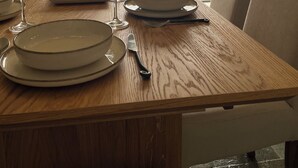 Une table à manger dressée avec des assiettes, des verres et des couverts, donnant sur une étendue d’eau avec des montagnes à l’horizon.