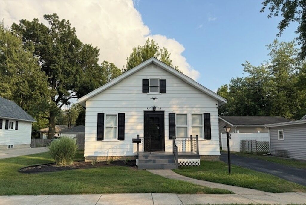 A single-story house with a front porch, a black front door, and a small front yard.