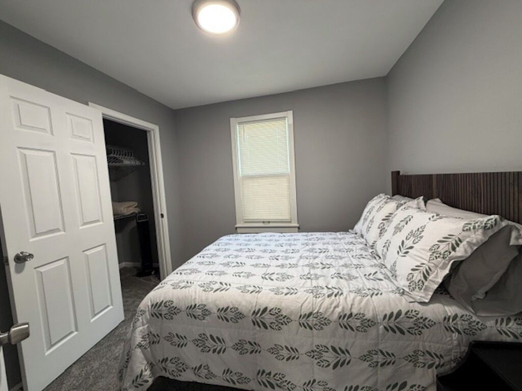 A bedroom with a bed, a closet, and a window.