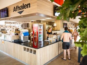 Um balcão de comida com um letreiro que diz 'Afhalen' em um ambiente interno moderno.