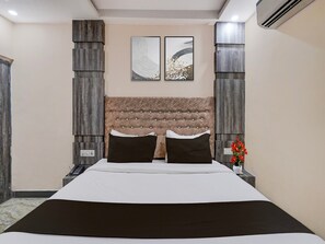 Ein Schlafzimmer mit einem großen Bett, einem gepolsterten Kopfteil, zwei Nachttischen und einer Wand-Klimaanlage.