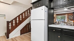 A kitchen with dark wooden cabinets, a white refrigerator, and a wooden staircase. - Rocky’s Riverside Retreat - heated pool, river access (Estes Park)