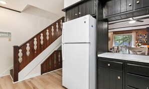 Una cocina con armarios de madera oscura, un refrigerador blanco y una escalera de madera.