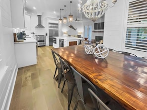 A modern kitchen with stainless steel appliances, a wooden dining table, and pendant lighting. - Spacious 4-bedroom house in beautiful Inlet Beach Florida w heated pool (Seacrest)
