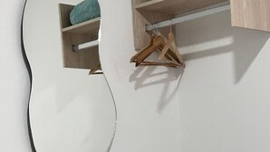 A bathroom with a large mirror, wooden shelf with a teal towel, and a rolled white towel on the floor. - HOTEL LA ESTRELLA DE DAVID  (Cartagena)