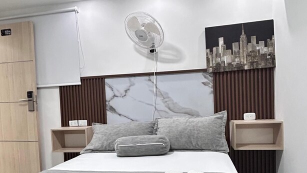 A modern bedroom with a bed, two bedside tables, a wall-mounted air conditioner, and a cityscape painting. - HOTEL LA ESTRELLA DE DAVID  (Cartagena)