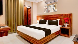 Een hotelkamer met een houten bed, een televisie, een bureau en een airconditioning.