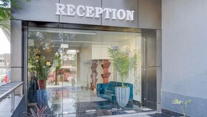 Een receptie met een glazen deur, plantenpotten en een blauwe bank.