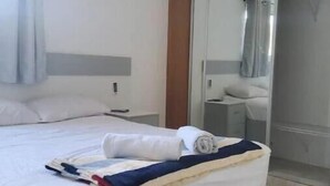 Een hotelkamer met een bed, nachtkastje, spiegel en een douche.
