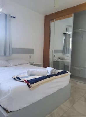 A hotel room with a bed, a nightstand, a mirror, and a shower area. - Nice two-bedroom apartment (Sosúa)