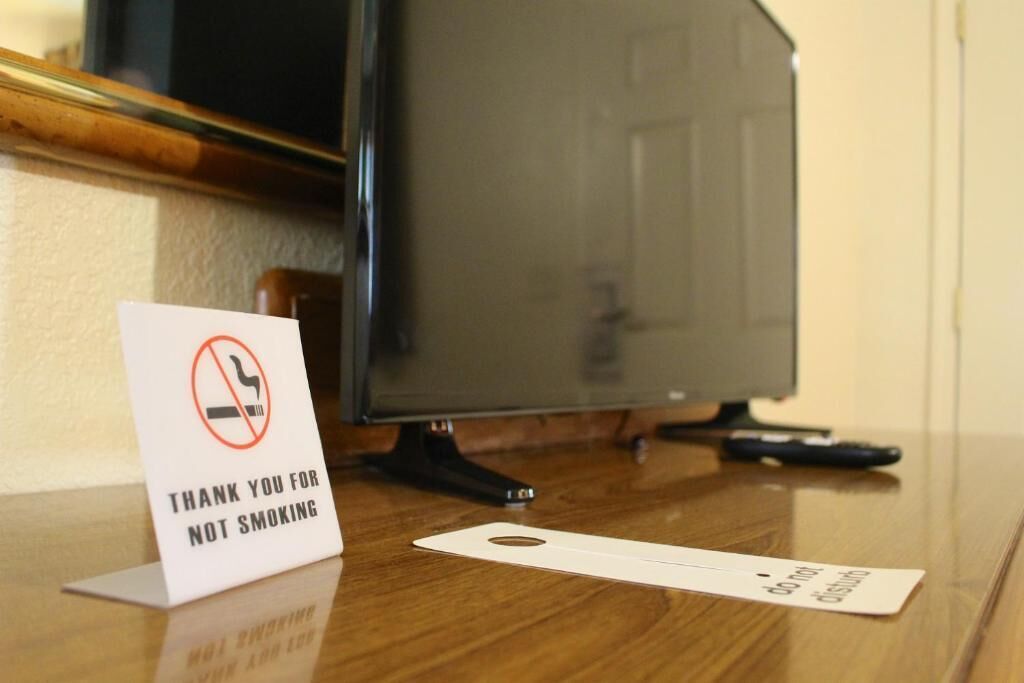 A no-smoking sign and a 'Do Not Disturb' sign on a wooden surface near a television.