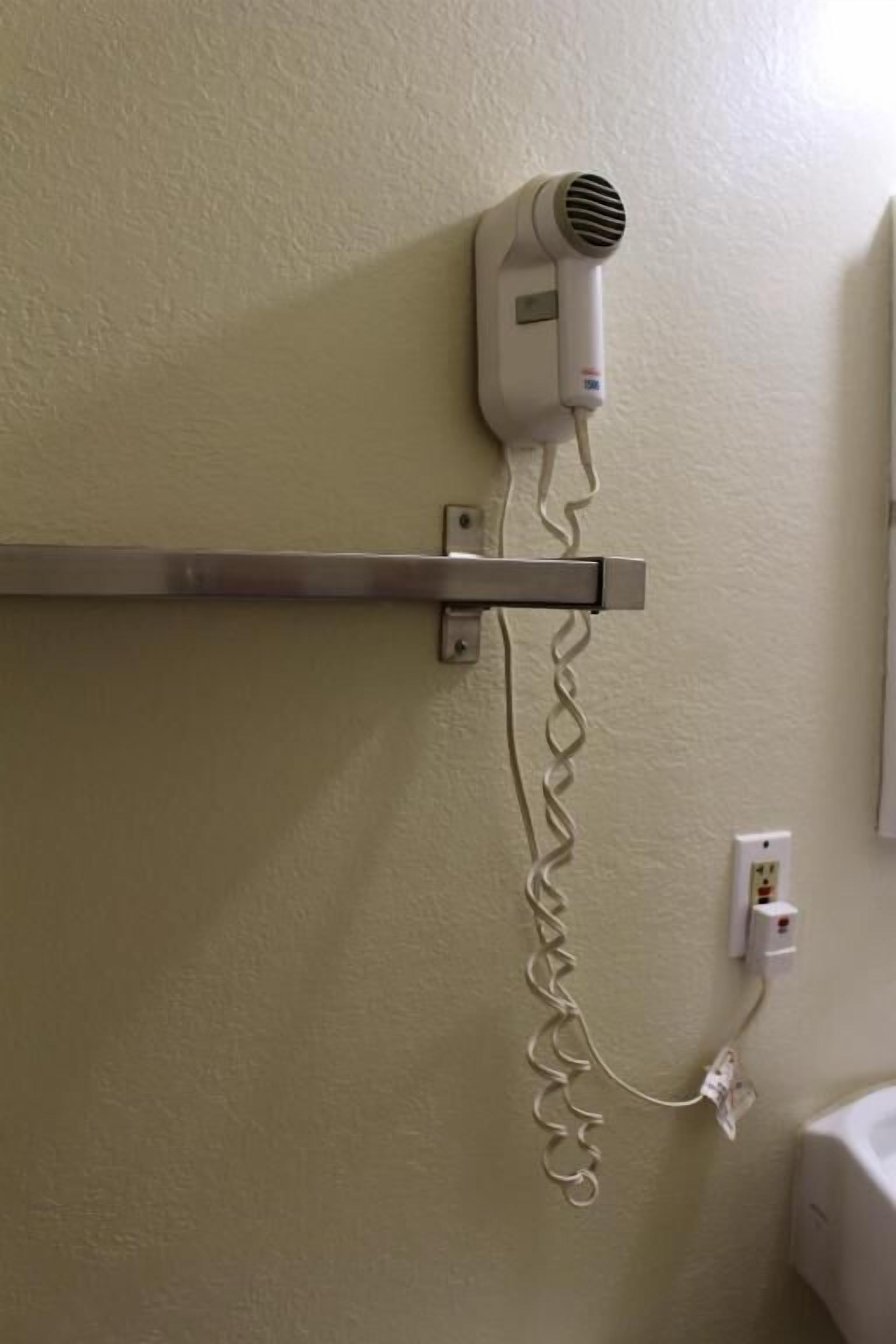 Ein an der Wand befestigter Haartrockner mit Kabel.