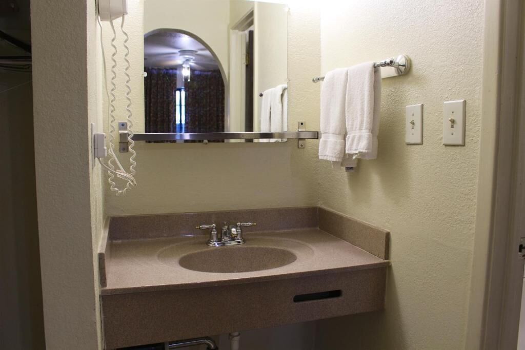 Un baño con lavamanos, espejo, toallero y teléfono.