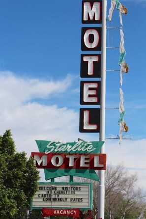 A motel sign with neon lights spelling 'MOTEL' and a green banner with 'Starline Motel' text. - Starlite Motel (Mesa)