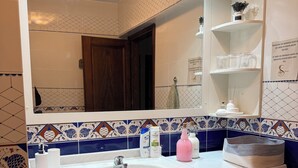 Une salle de bain avec un lavabo, un miroir, un lave-linge et des murs carrelés.