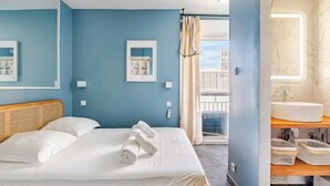 Een hotelkamer met een bed, een badkamer met een wastafel en uitzicht op buiten.