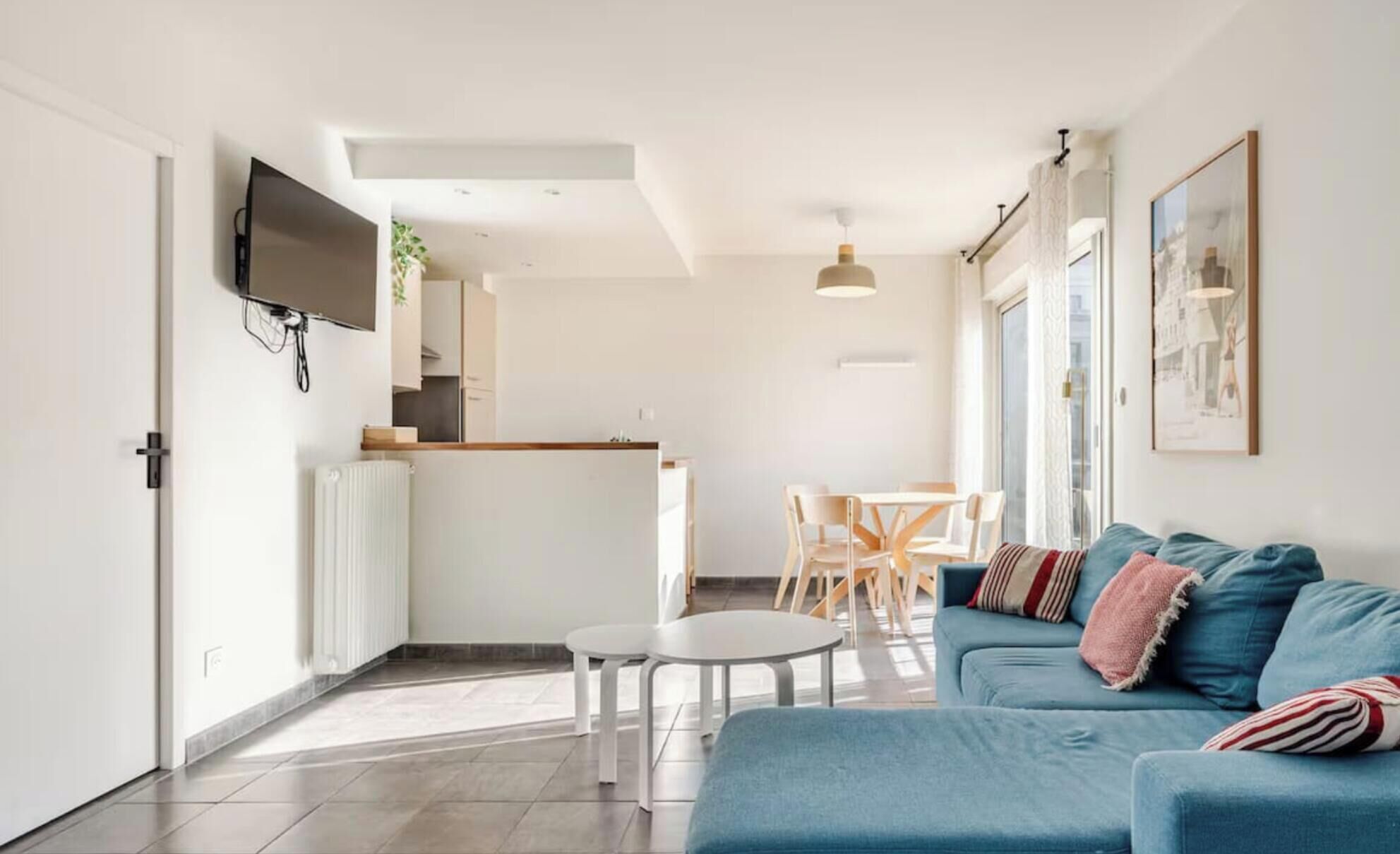 Een moderne woonkamer met een blauwe bank, een witte salontafel en een eethoek met stoelen.