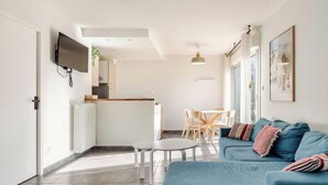 Een moderne woonkamer met een blauwe bank, een witte salontafel en een eethoek met stoelen.