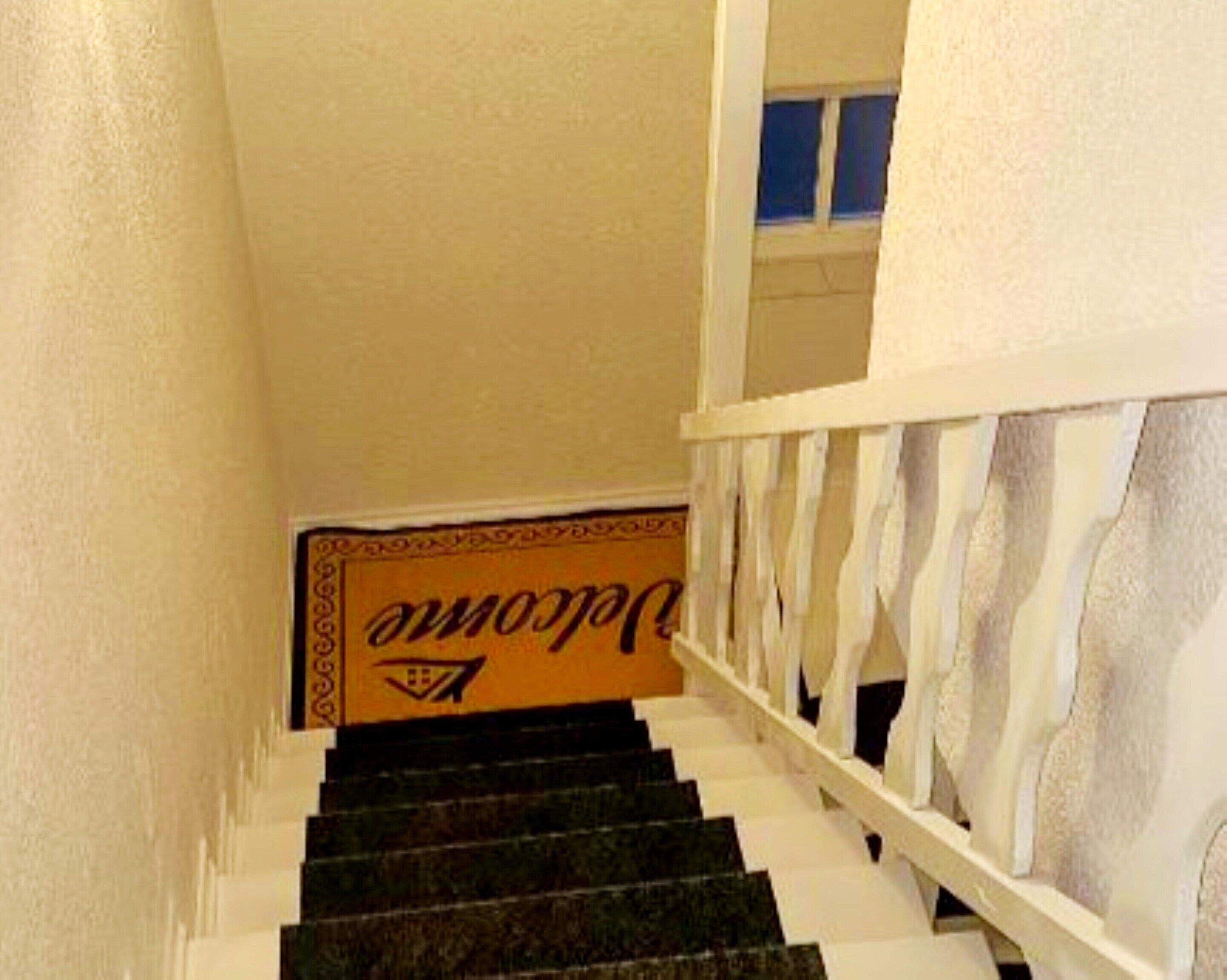 A staircase with a white railing and a sign with a logo.