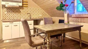 A dining area with a table and chairs, a kitchen with patterned backsplash, and a window with a view. - Gemutliche Wohnung in Konz an der Mosel (Konz)