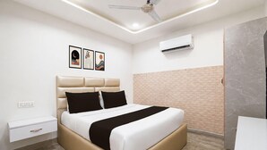 A modern bedroom with a bed, nightstand, wall art, and an air conditioning unit.