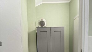 Un couloir avec une armoire grise, une porte blanche et un plancher en bois.