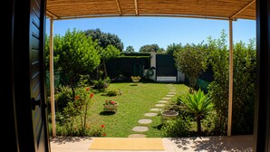 A garden with a paved path, potted plants, and a flamingo statue. - Terraced house with private garden Costa Rei, 300 meters from the sandy beach. (Costa Rei)