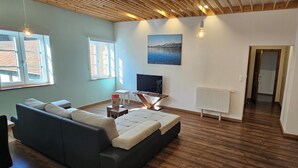 A modern living room with a sofa, TV, and artwork on the wall. - The lake: 4 persoonsappartement op een boerderijsetting (Schloss Treffen)