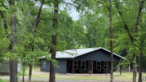 A cabin with a gravel driveway, surrounded by trees. - Wild Ride Retreat near Albert Pike Caddo River ATV trailer parking Pets allowed (Caddo Gap)
