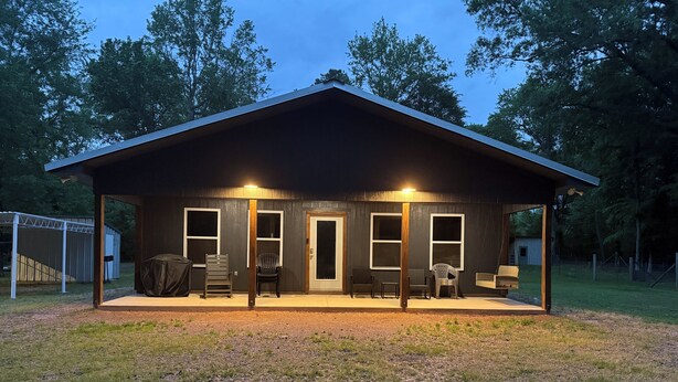 A covered outdoor area with a wooden structure, two windows, and a door. - Wild Ride Retreat near Albert Pike Caddo River ATV trailer parking Pets allowed (Caddo Gap)