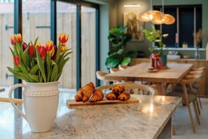 Une cuisine avec un plan de travail en marbre, un pichet blanc orné de tulipes et des croissants disposés sur une planche en bois.