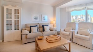 Un salon comprenant un canapé, des fauteuils, un meuble et une table.