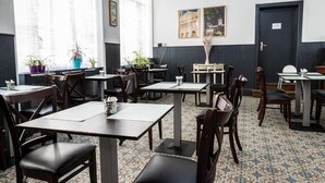 Un restaurante con mesas y sillas, plantas en macetas y cuadros en las paredes.