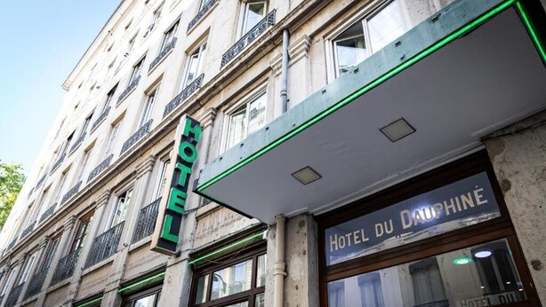 Fachada de hotel con un letrero que dice 'HOTEL DU DAUPHINÉ', amplias ventanas y un estilo arquitectónico clásico.