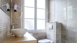 Un baño con un ventanal grande, un lavamanos blanco y un inodoro.