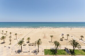A beach with palm trees, a lifeguard tower, and a clear sky. - AG GÓNDOLA 8 - only families (Playa de Gandía)