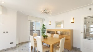 Uma sala de jantar com mesa de madeira, cadeiras, um lustre e um vaso com planta.