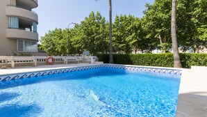 A swimming pool with a tiled edge, surrounded by a low wall and a bench. - VORAMAR II - only families (Playa de Gandía)