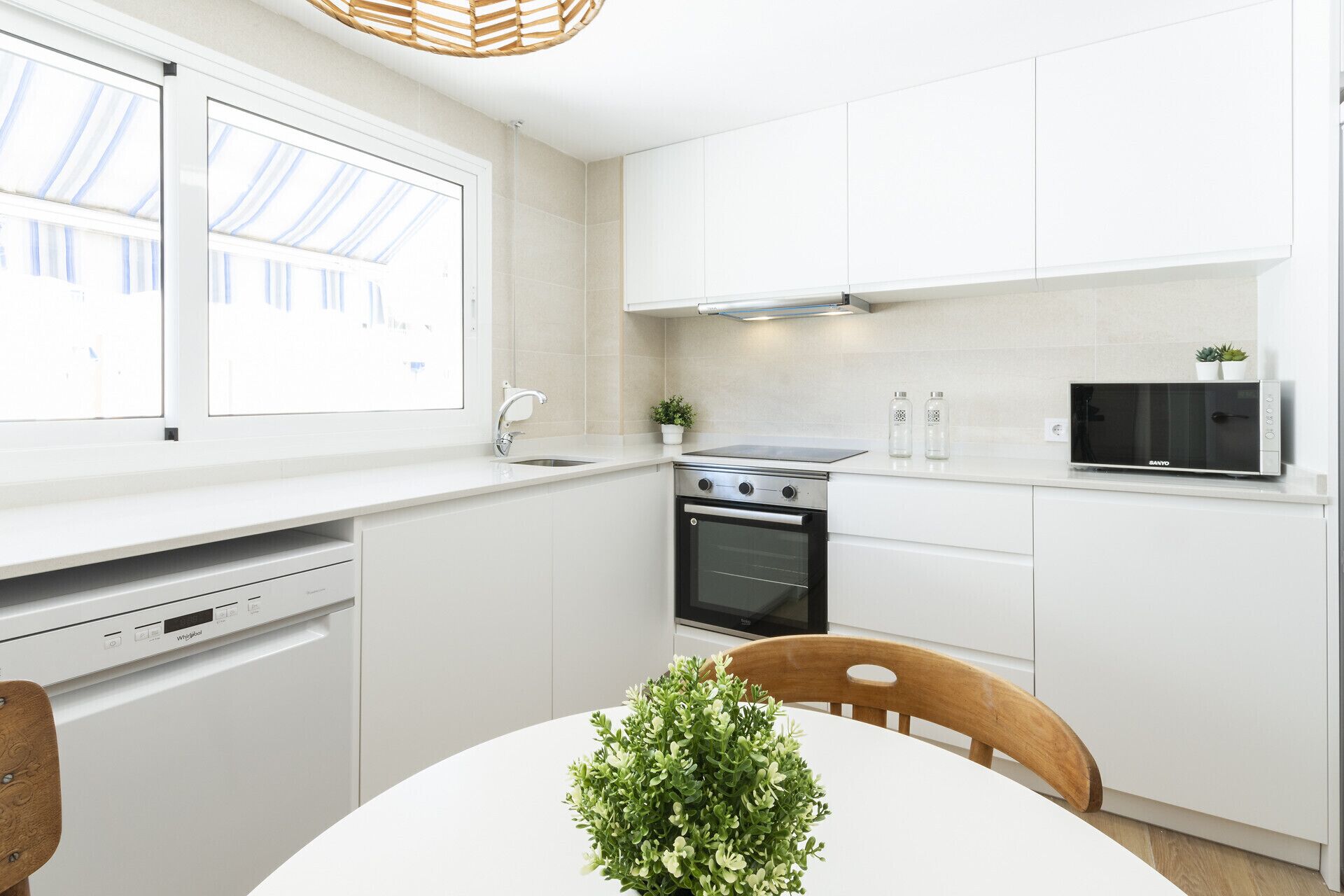 A modern kitchen with white cabinets, a built-in oven, a microwave, and a dishwasher.
