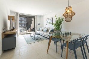 A modern living room with a glass dining table, a sofa, and a large window. - AG. ÁTICO ALAMO 9C - only families (Playa de Gandía)