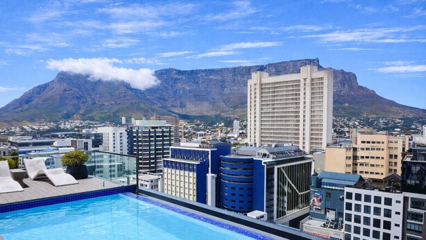 Ein Pool auf dem Dach mit Blick auf die Stadt und Berge im Hintergrund.