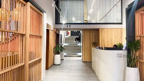 Eine Hotelhalle mit Empfangsschalter, einer Treppe und Holzvertäfelung.